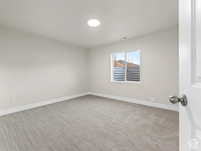 Recessed ceiling lighting, light gray wall paint, white trim, textured carpet flooring, and a single window