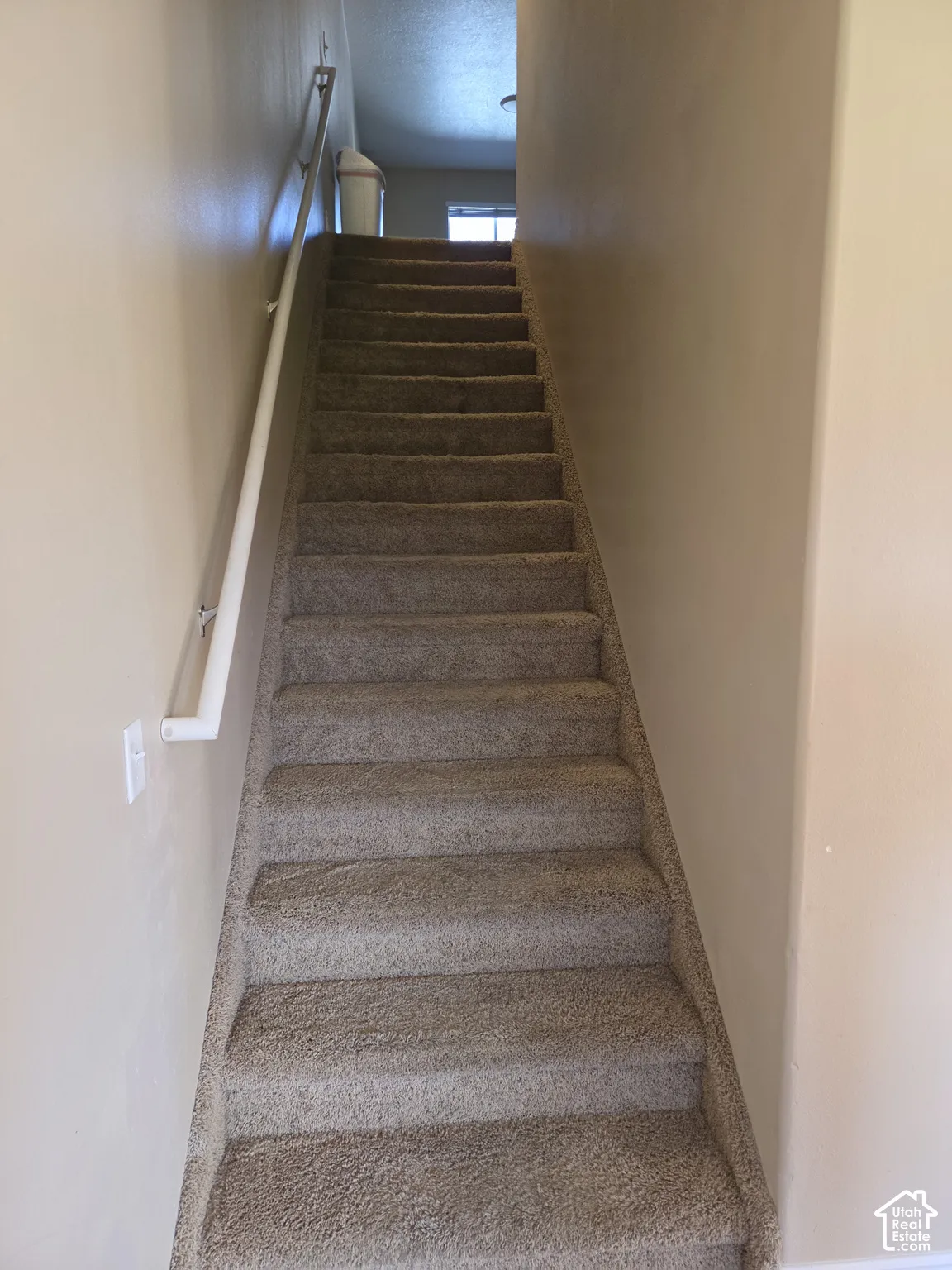 Carpeted staircase with a white handrail