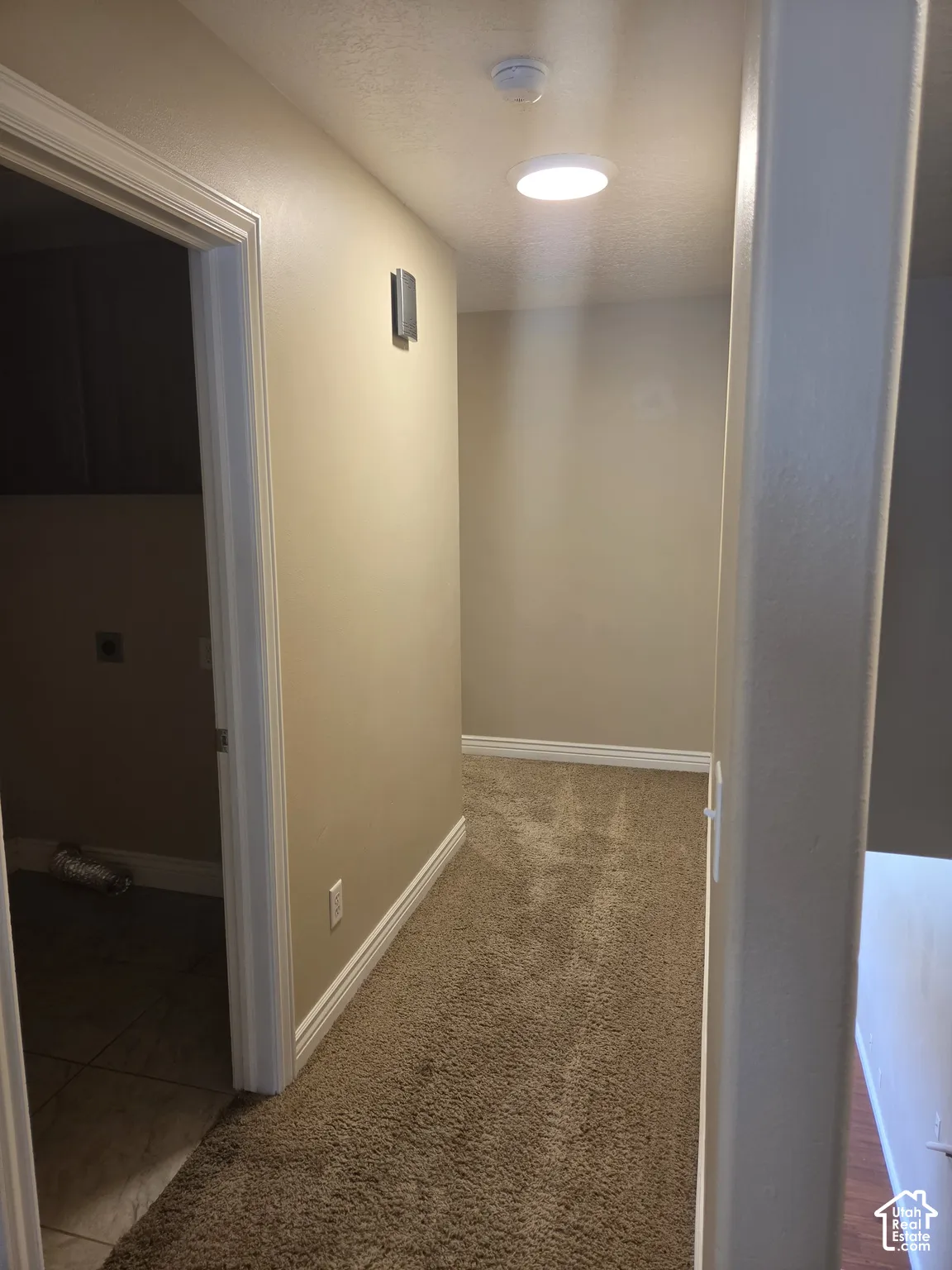 Hallway with recessed ceiling lighting, wall-mounted light fixture, and textured carpet flooring