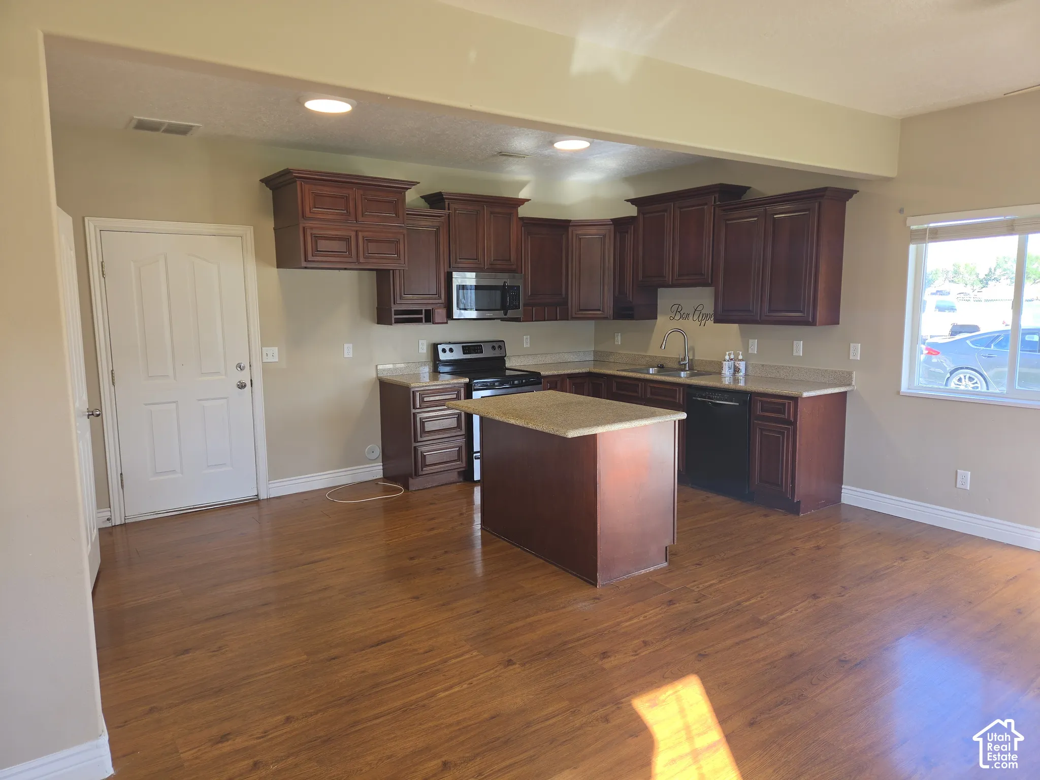 Kitchen featuring wood-finish flooring, dark wood cabinetry, light-toned countertops, and a center island