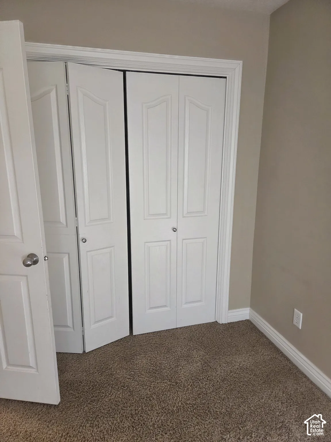 Neutral wall color, carpeted flooring, white trim, white doors, and bi-fold doors