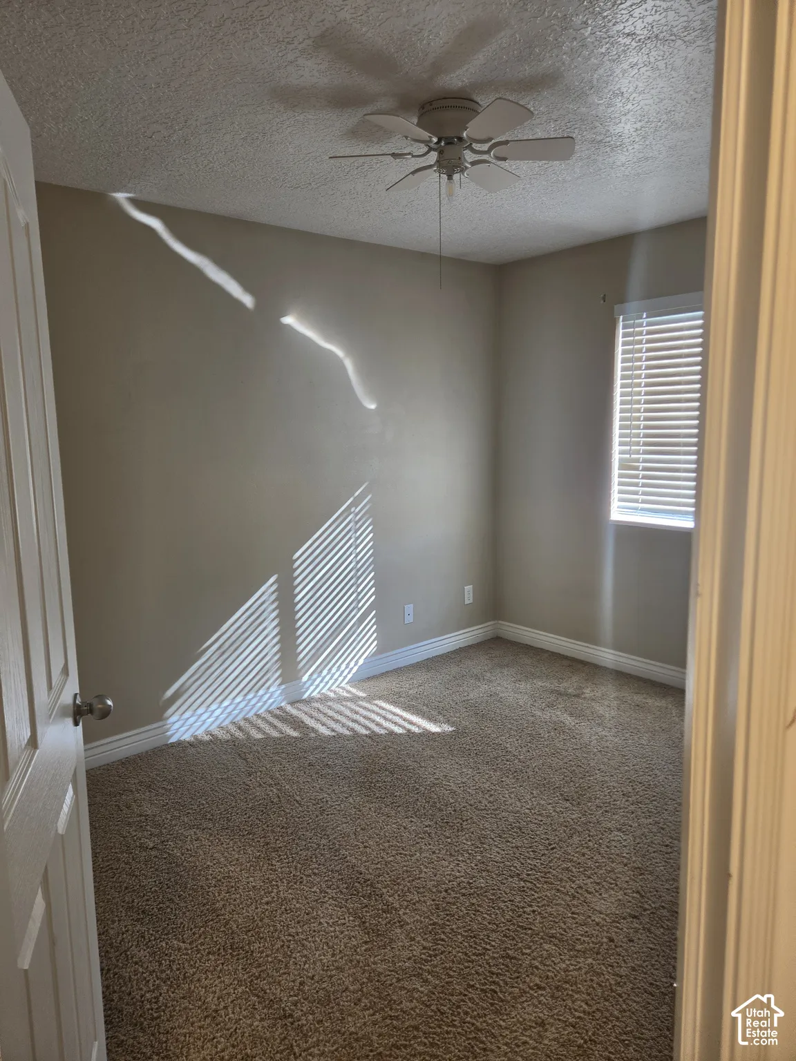Carpeted room featuring a ceiling fan with integrated lighting, a window with horizontal blinds, and neutral wall paint