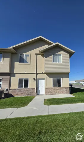 Two-story exterior with stucco and horizontal siding, brick-veneer base, and a concrete walkway