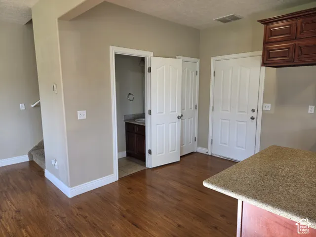 Wood-finish flooring, staircase with carpeted treads, built-in cabinetry, and a stone-finish countertop