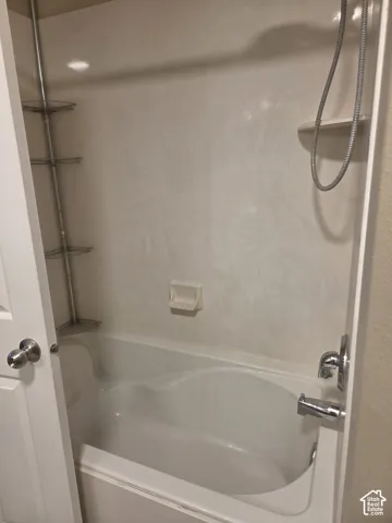 Alcove bathtub with white surround, integrated soap dish, and chrome fixtures