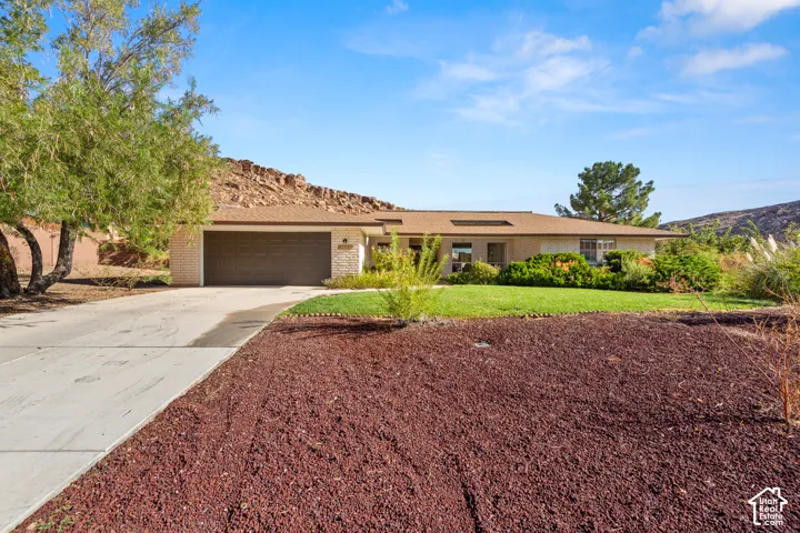 Single-story residence featuring a two-car garage, concrete driveway, and front landscaping with turf and decorative rock