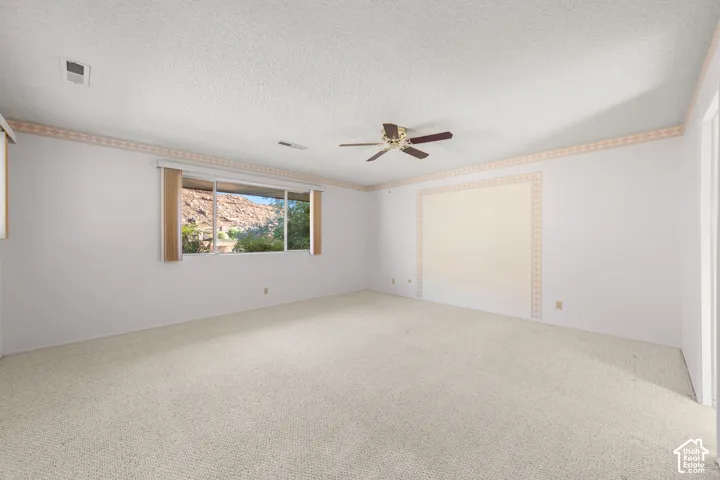 Wall-to-wall carpeting, ceiling fan, and window with natural scenery