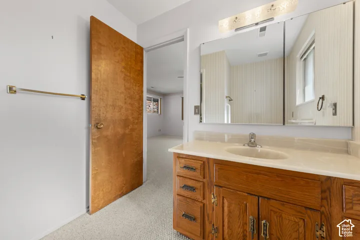 Vanity with a light-toned countertop, undermount sink, and wood-finish cabinetry
