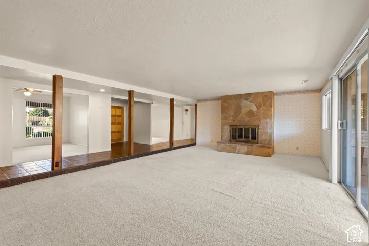 Spacious room featuring carpeting, a stone-clad fireplace, and sliding glass doors