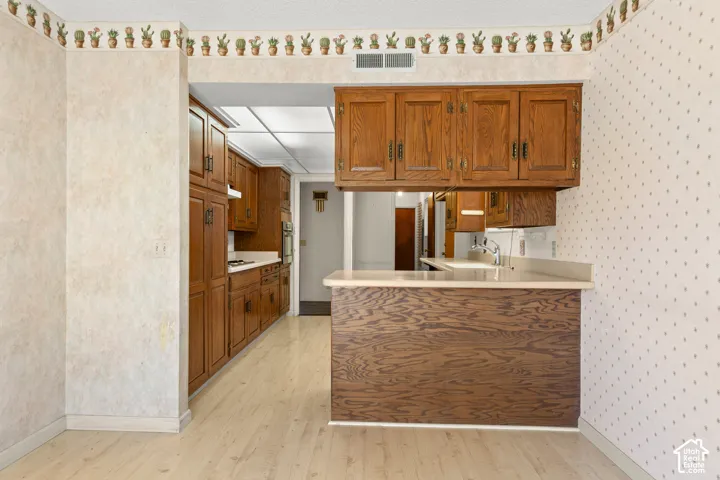 Wood-finish flooring throughout, full-height cabinetry, built-in cooktop, and a breakfast bar with countertop