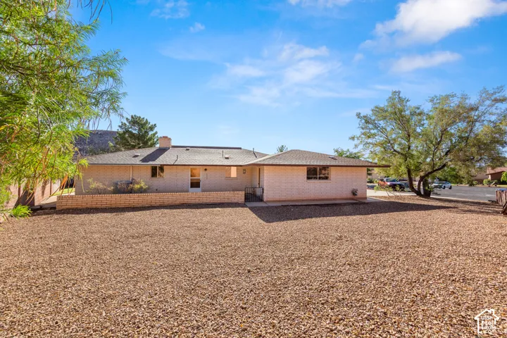 Rear exterior featuring brick siding, a low-pitched roof, and a gravel ground cover