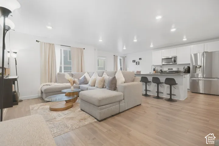 Open-concept living area with wood-finish flooring, recessed lighting, and white walls