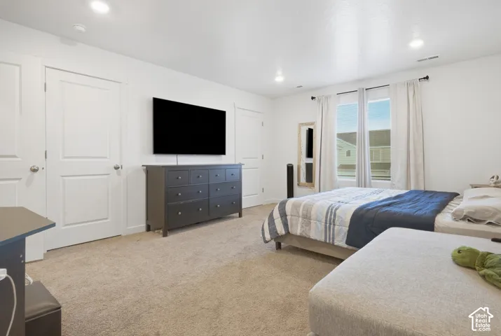 Recessed lighting, light-toned carpeting, multiple paneled doors, and a double window with vertical blinds