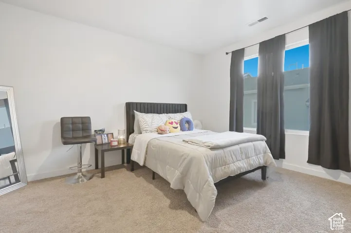 Wall-to-wall carpeting, white walls, and a window with dark drapery