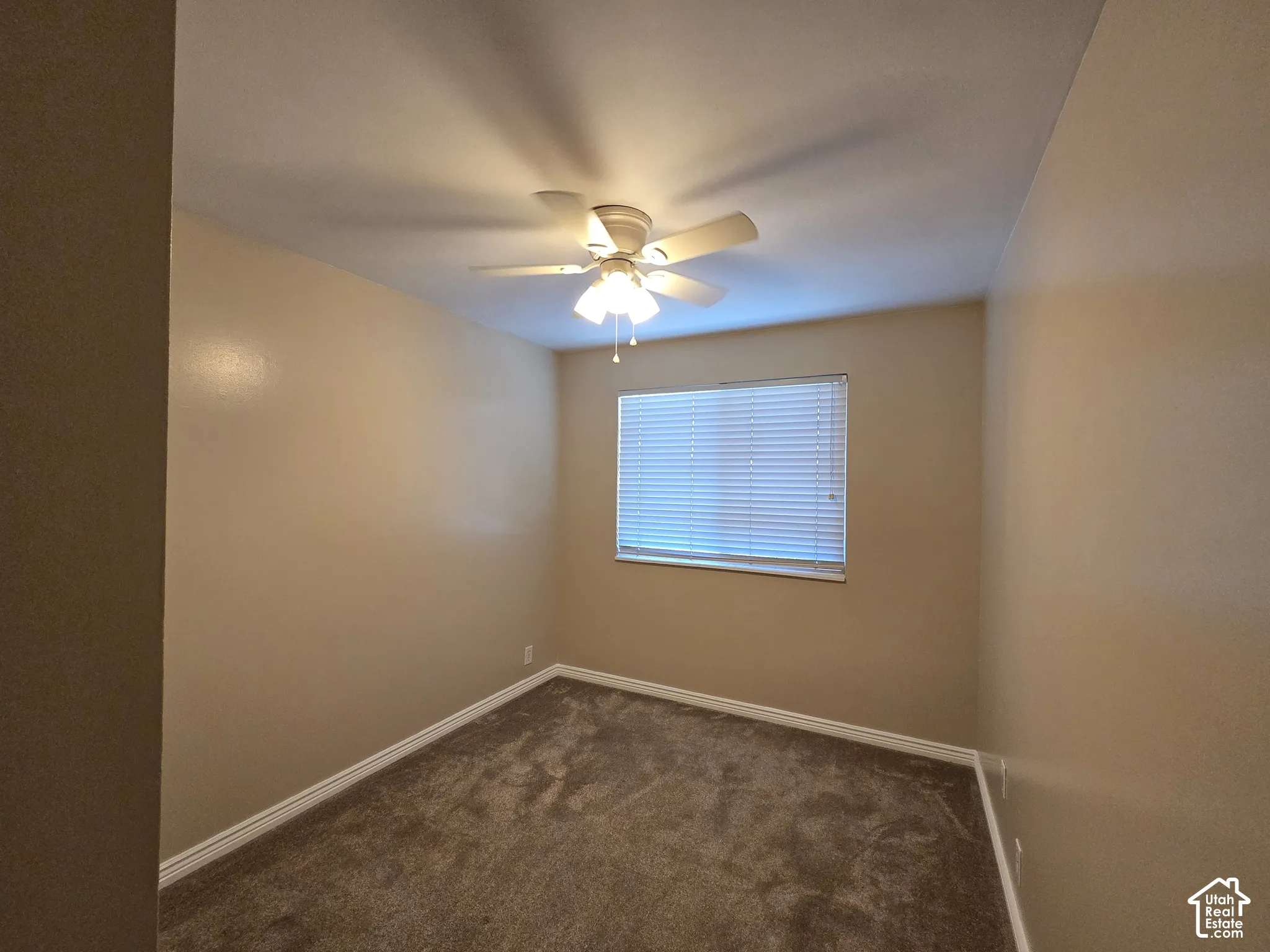 Recessed window with blinds, ceiling-mounted fan, and carpeted flooring