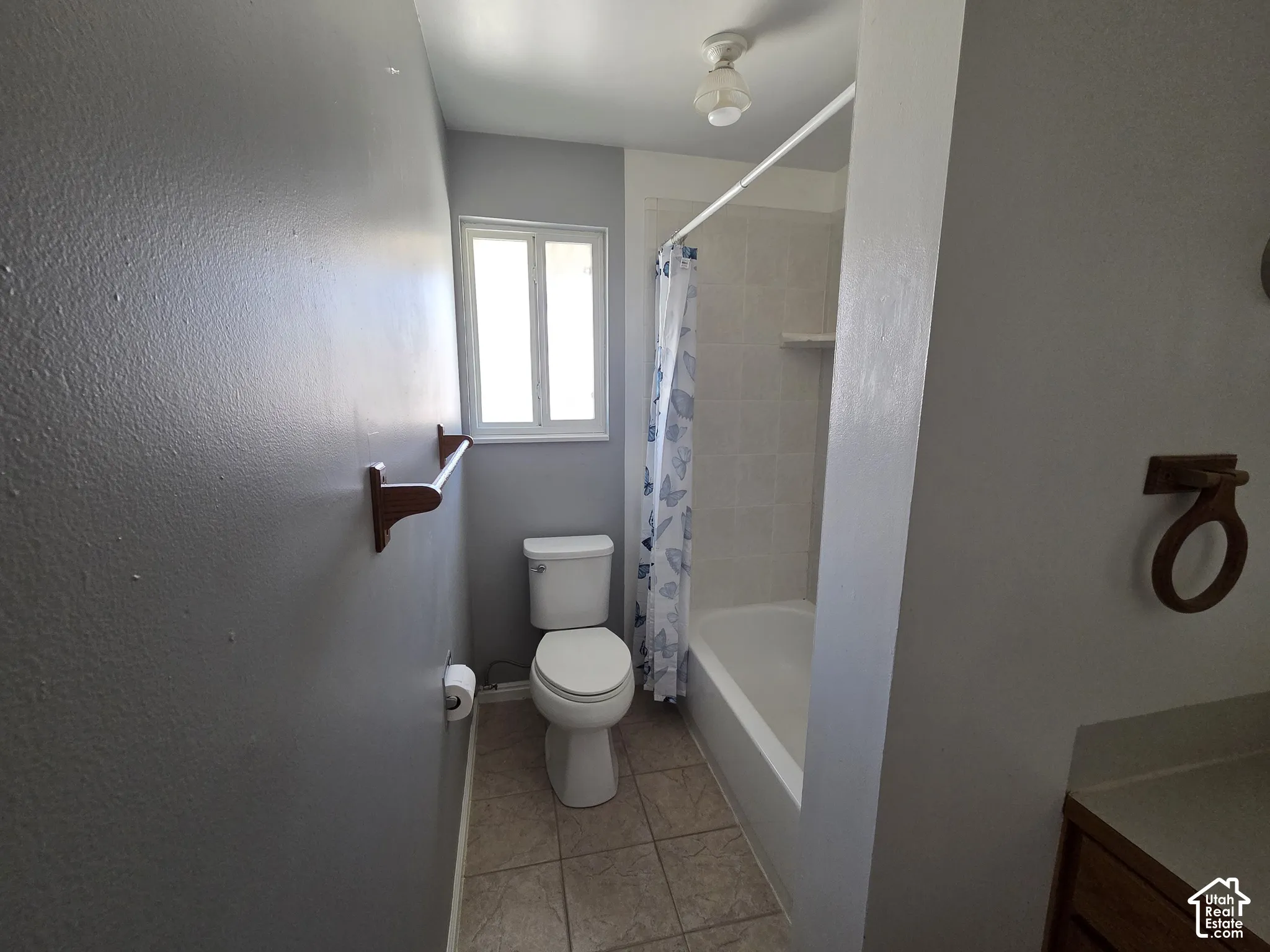 Bathroom featuring a built-in tub with tile surround, a window providing natural light, and a toilet