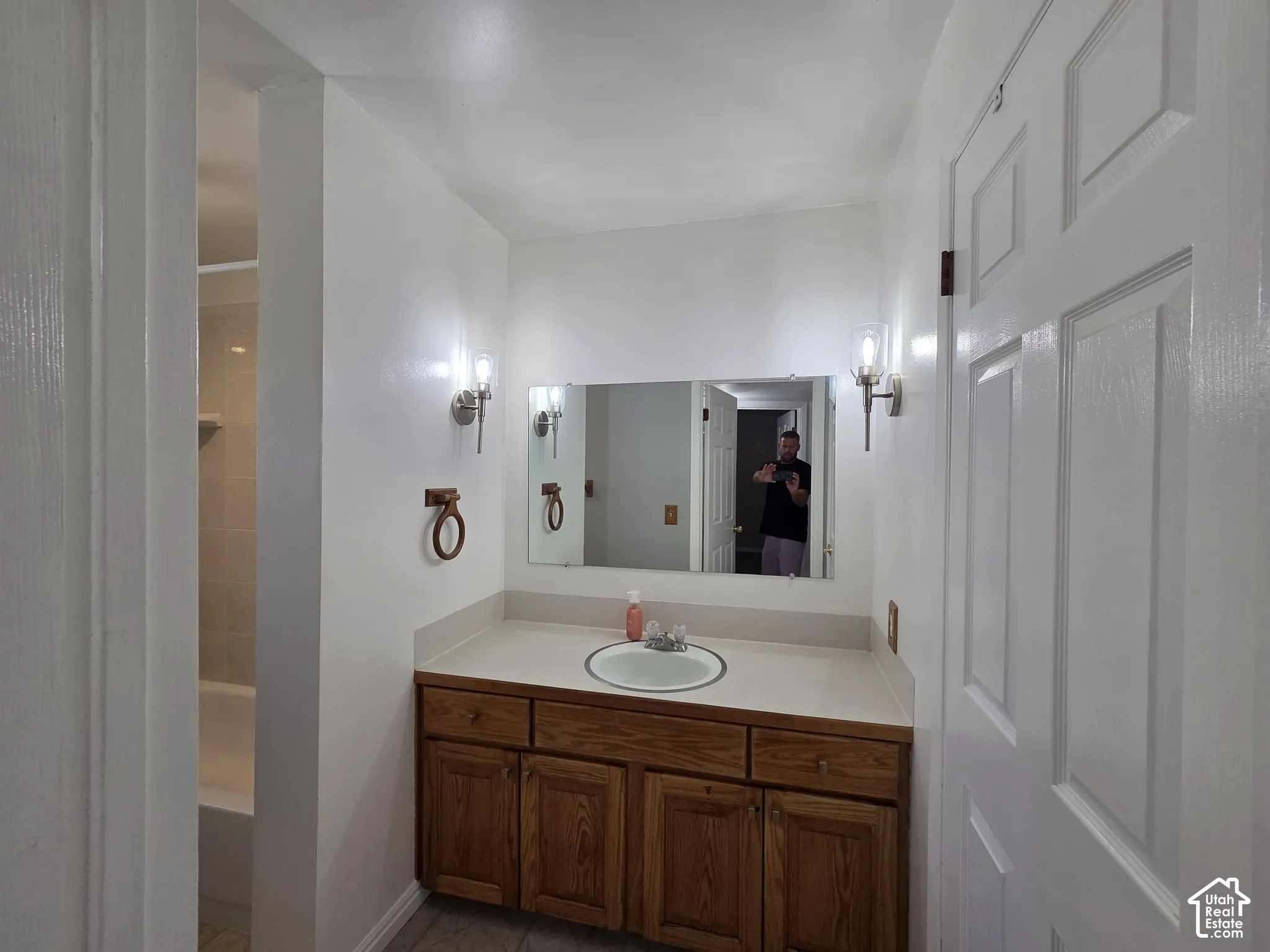 Bathroom featuring a single vanity with wood cabinetry, a built-in basin, and an integrated countertop