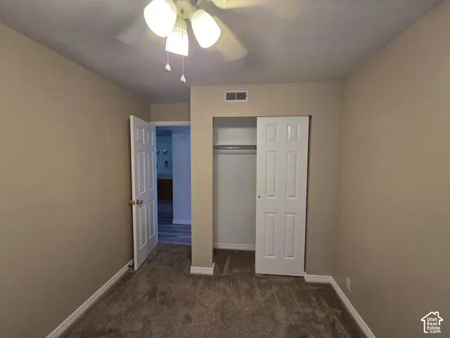 Ceiling fan light fixture, neutral carpet, bi-fold closet doors, white paneled doors, and neutral wall paint
