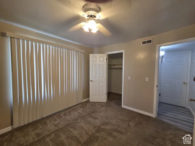 Carpeted room with a ceiling fan, vertical blinds, and a built-in closet.
