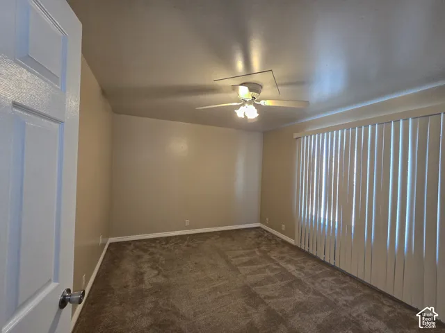 Carpeted room with vertical window blinds and a ceiling fan with integrated lighting