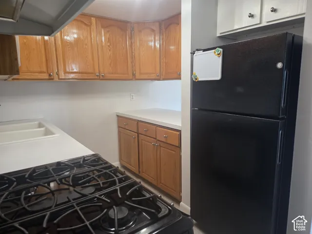 Kitchen featuring a black gas range, built-in upper and lower cabinetry, and a black refrigerator