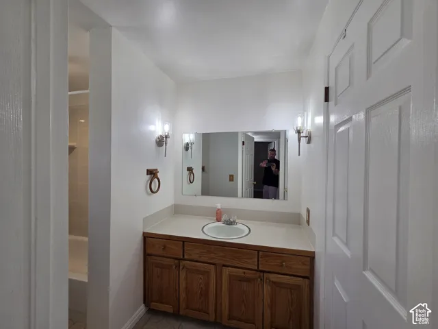 Bathroom featuring a single vanity with wood cabinetry, a built-in basin, and an integrated countertop