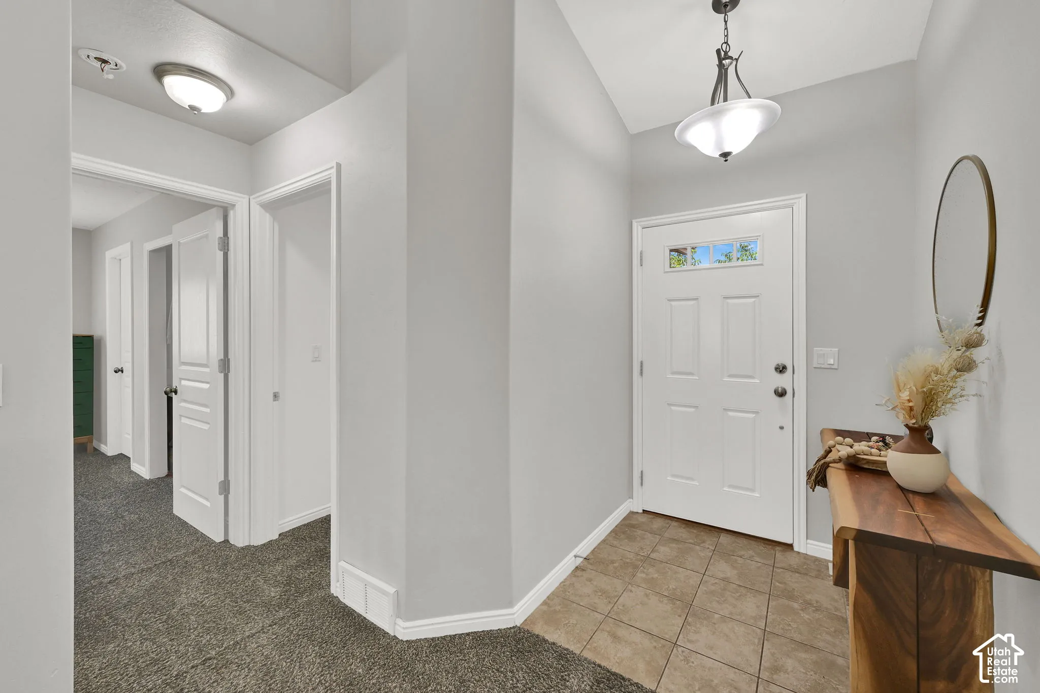 Entryway featuring tiled flooring, a white paneled door with upper window panes, and a modern pendant light fixture