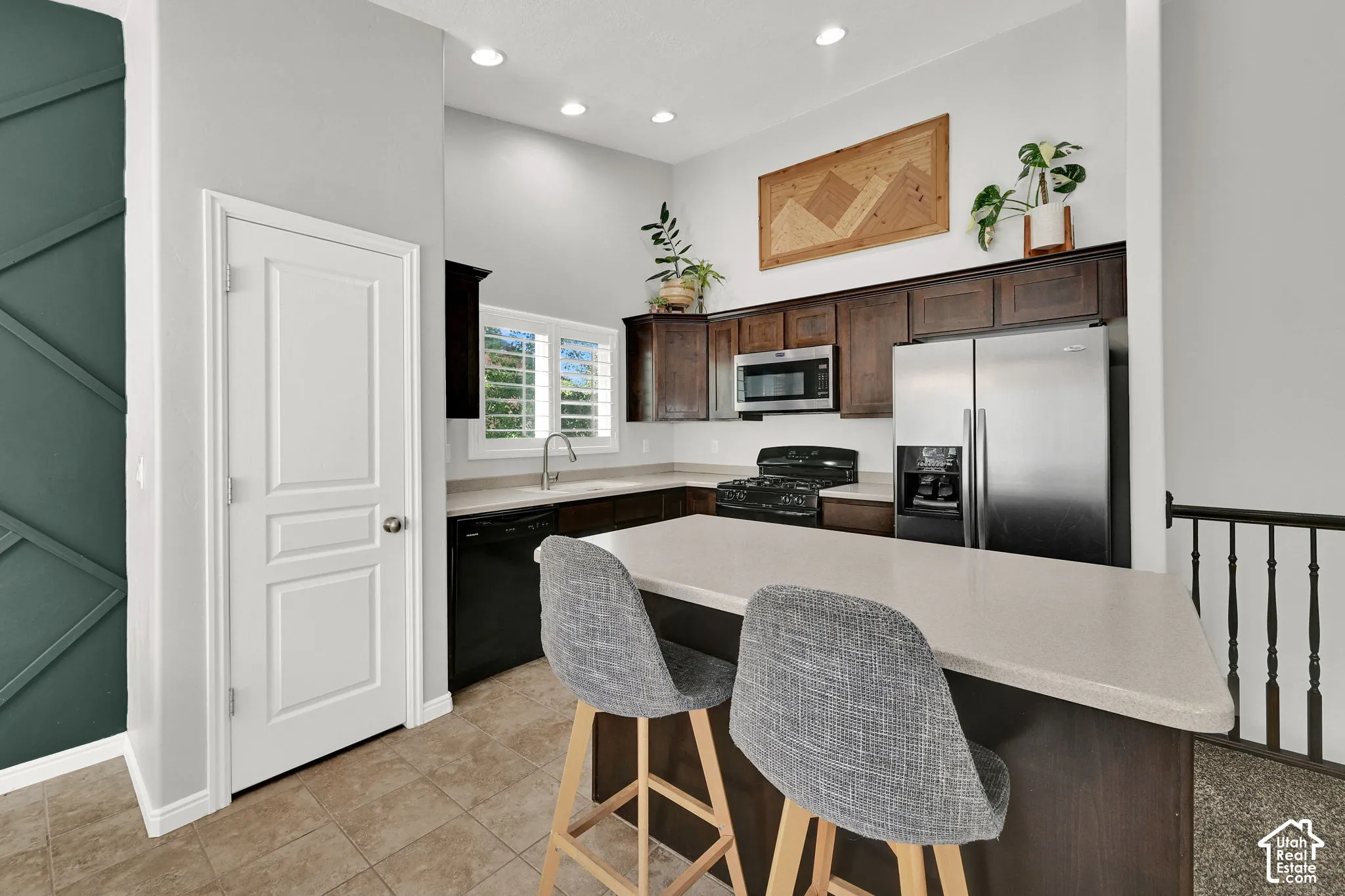 Kitchen featuring dark wood cabinetry, stainless steel appliances, light-toned countertops, and recessed lighting