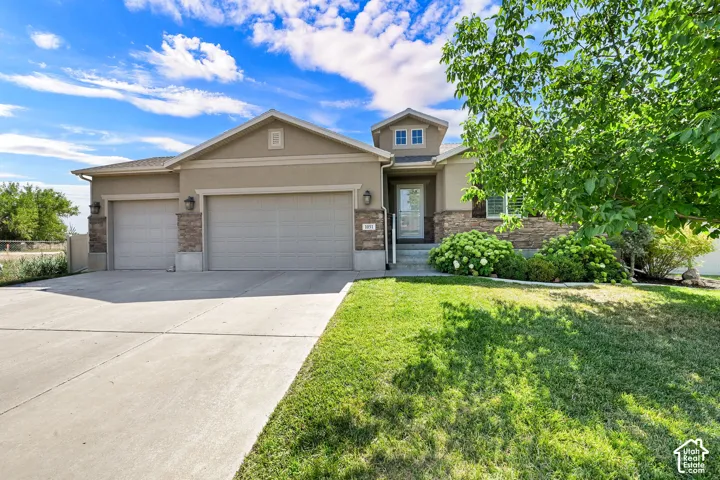 Multi-car driveway, attached two-car garage, stone accent siding, covered entryway, and mature landscaping