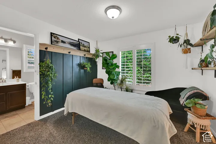Carpeted room with a dark green accent wall featuring a wood shelf and coat hooks