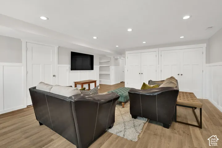 Recessed ceiling lighting, wood-finish flooring, white paneling, white trim, and built-in shelving