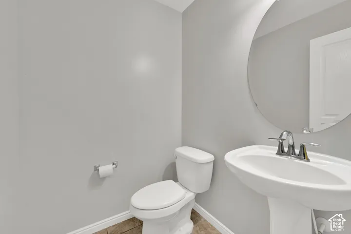 Pedestal sink with chrome fixtures and a circular wall mirror