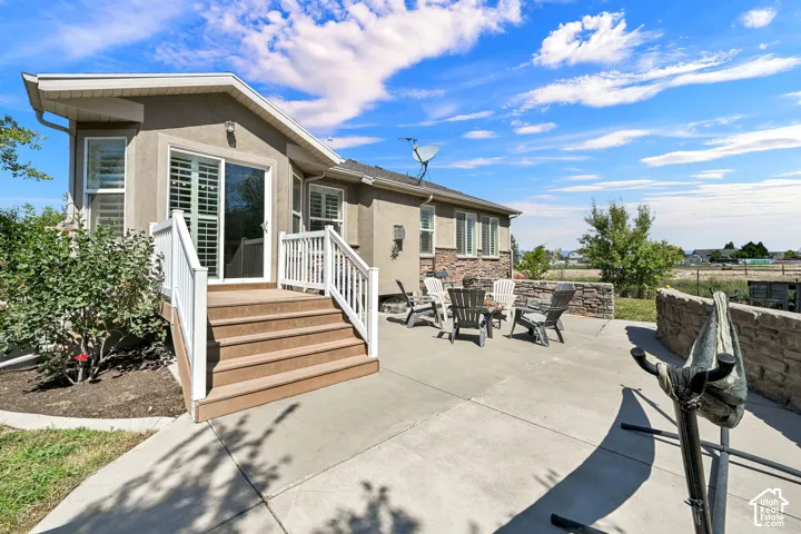 Rear exterior with a concrete patio, stone accent wall, and multi-level deck featuring white railings and composite steps