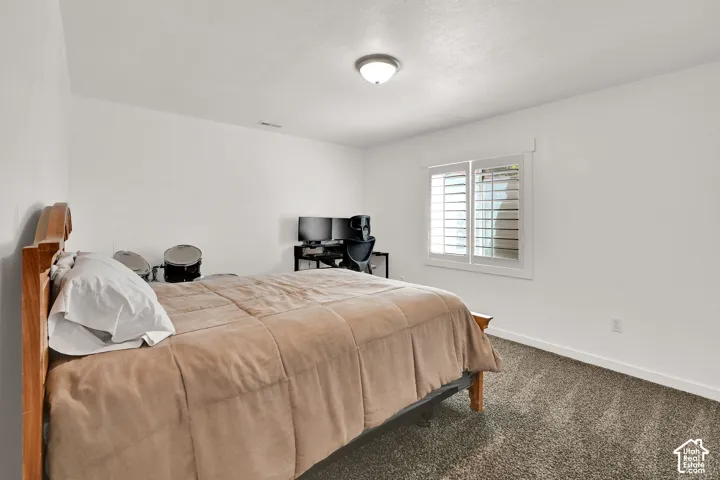 White walls with trim detail, a single window with plantation shutters, ceiling-mounted light fixture, and textured carpet flooring
