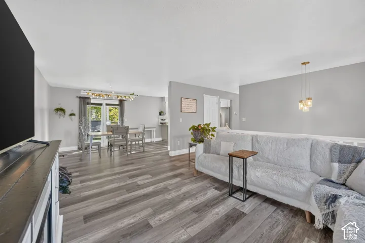 Wood-finish flooring throughout, light gray wall tones, recessed lighting, and a modern dining chandelier