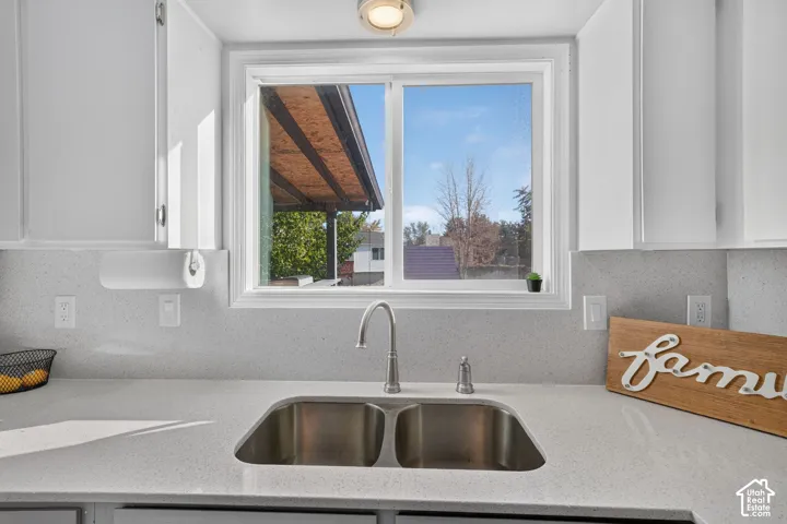 White shaker-style cabinetry, double basin stainless steel sink, brushed nickel faucet, and light-toned solid surface countertops