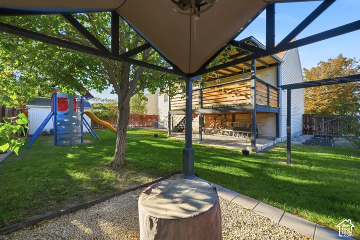 Expansive backyard featuring a manicured lawn, established tree, and a multi-level deck with wood-finish railing