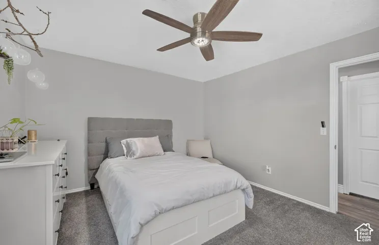 Ceiling fan with brushed nickel hardware and wood-finish blades, gray wall paint, gray carpet flooring, and white trim