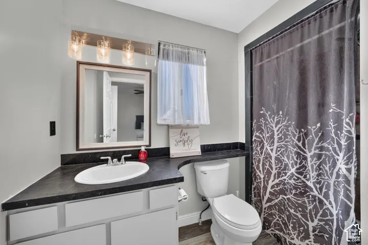White vanity with a single basin sink, dark countertop, and a framed mirror