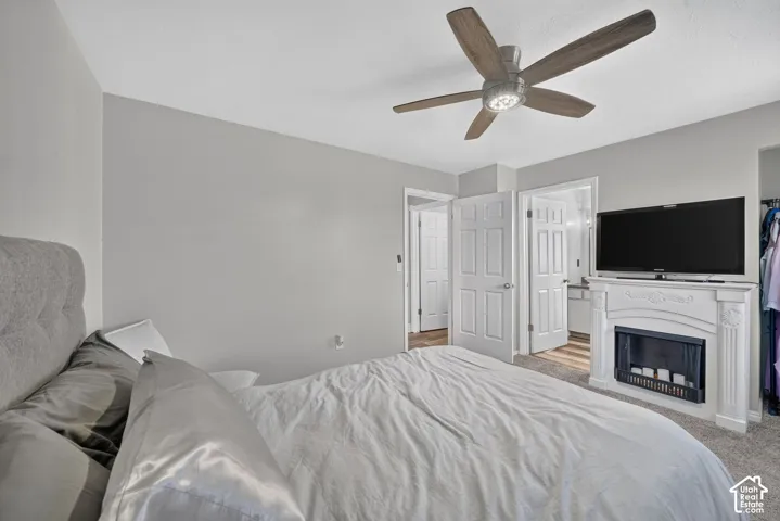 Ceiling fan with integrated lighting, built-in electric fireplace with mantel, two panel doors, and carpeted flooring