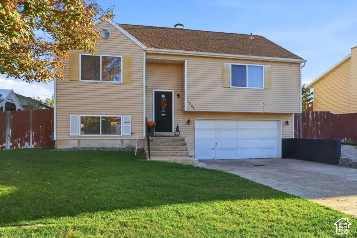 Two-story residence featuring light-colored siding, a brown shingle roof, a two-car garage, and a concrete driveway