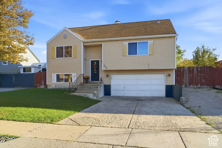 Exterior featuring light-colored siding, a front-facing garage, a concrete driveway, and a manicured lawn