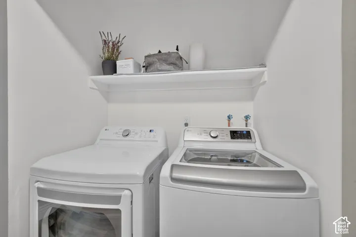Dedicated laundry area with built-in shelving, white walls, and bright overhead lighting