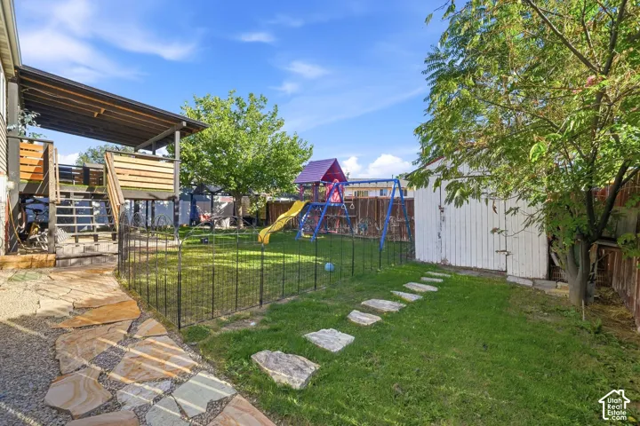 Expansive backyard featuring a stone paver pathway, manicured lawn, and a detached storage shed