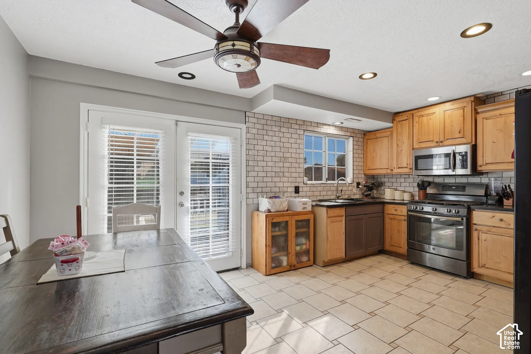 Kitchen featuring wood cabinetry, stainless steel appliances, tile flooring, and white subway tile backsplash