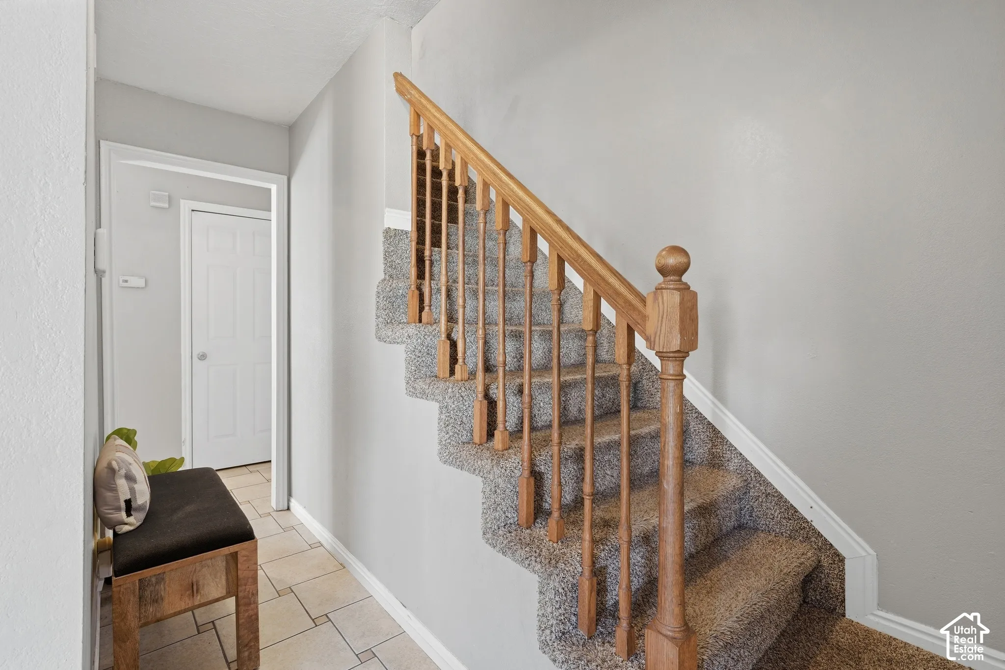 Staircase with light wood banister and carpeted treads, complemented by light gray wall finishes and white trim
