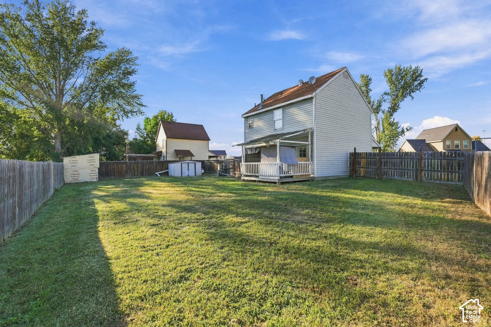 Expansive backyard featuring a manicured lawn, a covered porch, and a wood privacy fence