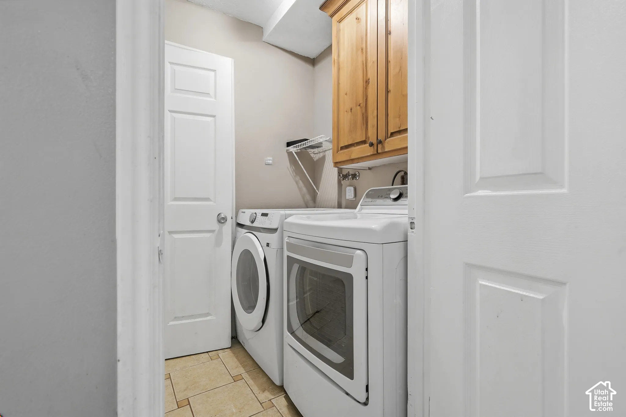Laundry area featuring wood-finish cabinetry, tile flooring, and a white paneled door
