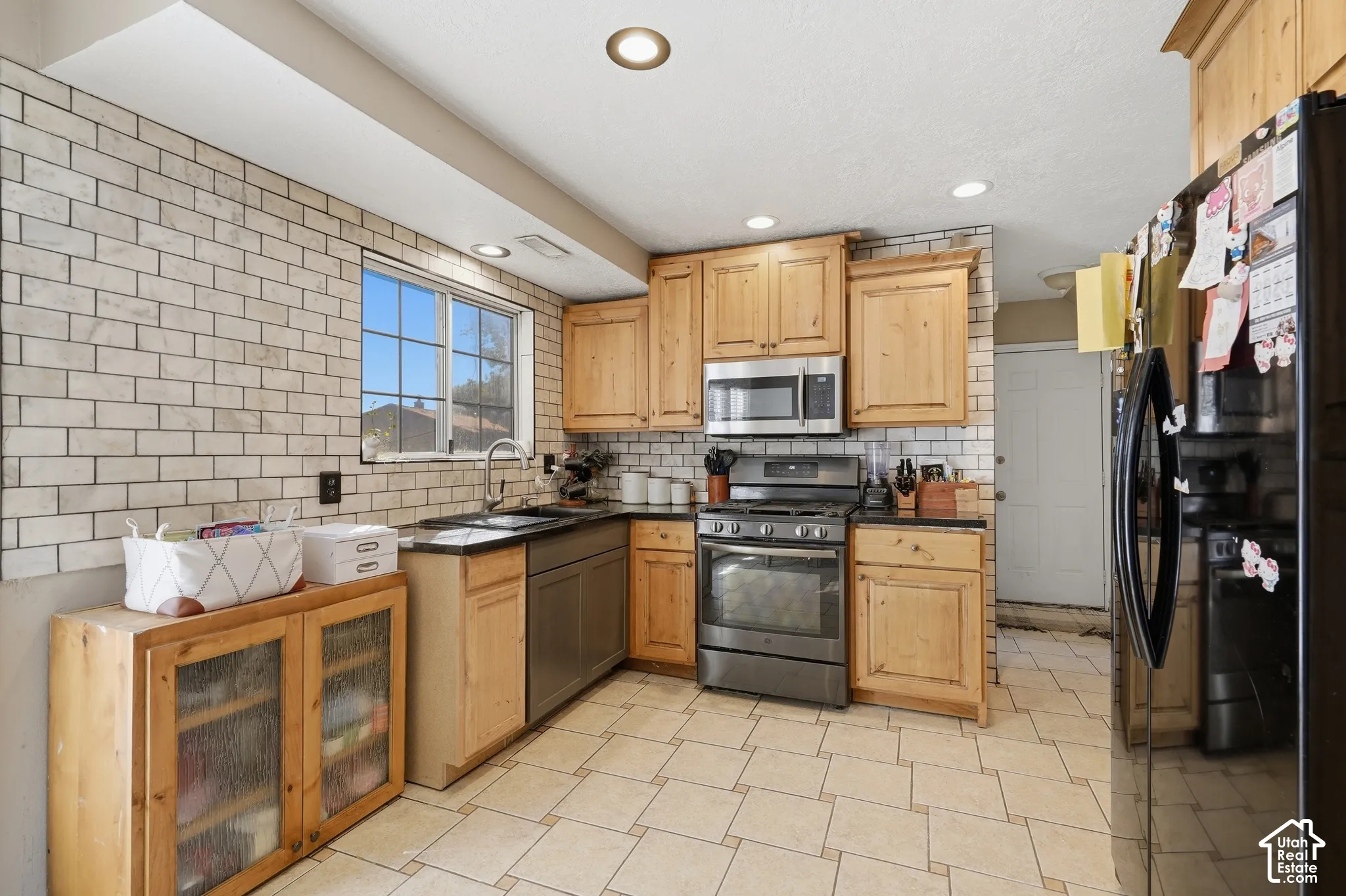 Kitchen featuring wood cabinetry, stainless steel appliances, a tile backsplash, and recessed lighting