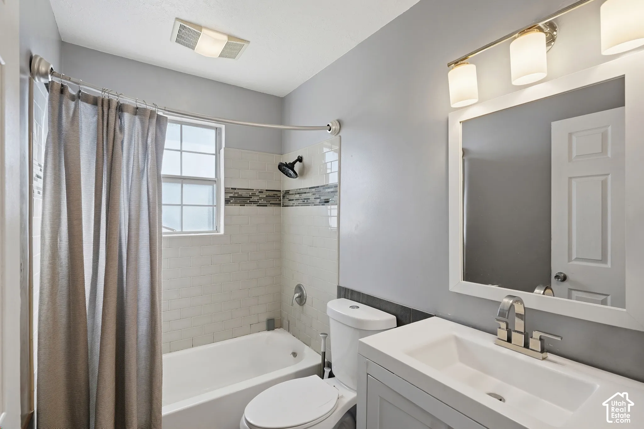 White subway tile shower surround with mosaic accent band, contemporary vanity with integrated sink, brushed nickel faucet, and a wall-mounted mirror